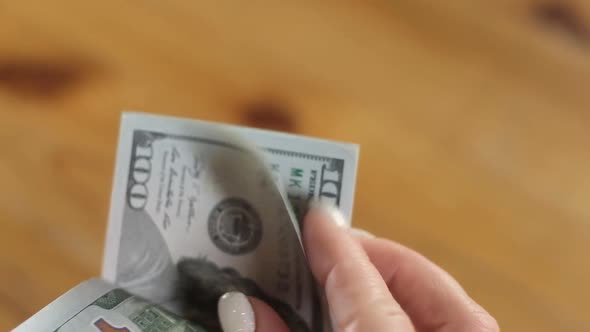 girl is holding stack dollar bills and counting money with manicured fingers.