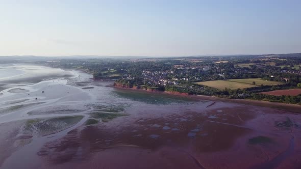 Flying towards the coast of Lympstone England during the day. Patches of agricultural land and the r