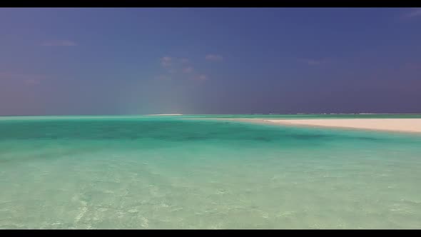 Aerial flying over texture of idyllic resort beach break by clear ocean with white sand background o