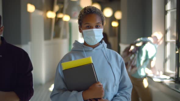 Student Wearing Face Protective Medical Mask for Protection From Virus with Book at Hallway