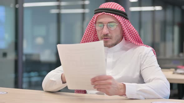 Middle Aged Arab Man Reading Documents in Office
