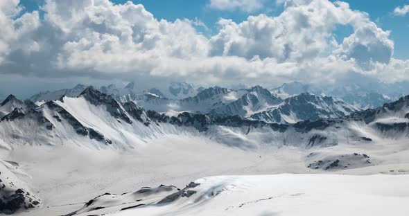 Air Flight Through Mountain Clouds Over Beautiful Snowcapped Peaks of Mountains and Glaciers