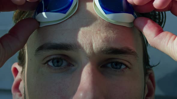 Close up of a male swimmer putting on the swimming glasses