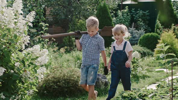 Little Boy and Girl with Shovel in Garden