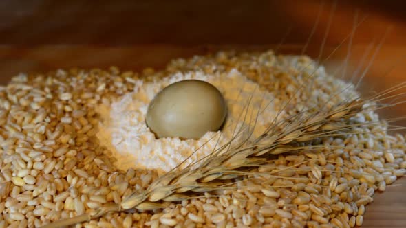 Wheat grains, wheat ears, flour, eggs and bread slices on wooden table