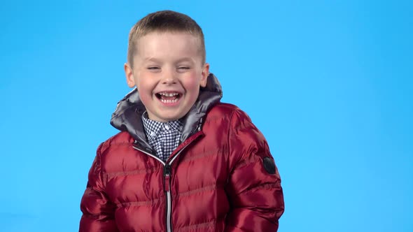 Boy Laughing Loudly, Looking at Camera, Posing Against Blue Background.