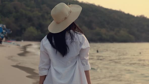 Beautiful Asian girl tourist walking on the beach during sunset.