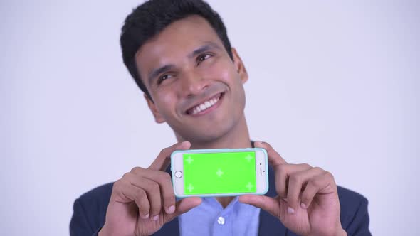 Face of Happy Young Indian Businessman Thinking While Showing Phone