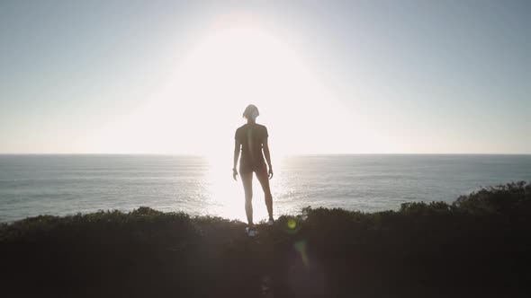 Sportswoman silhouette admiring seashore at sunset