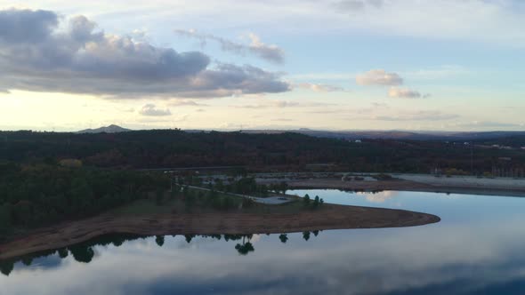 Drone aerial view of a lake reservoir of a dam with perfect reflection on the water of the sunset in