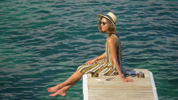 A woman with a glass of white wine on a dock over the Mediterranean Sea in Italy, Europe