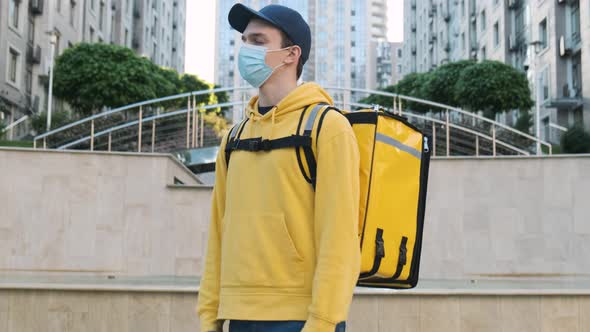 Portrait of Young Courier Delivery Man Wearing Yellow Uniform and Protective Face Mask