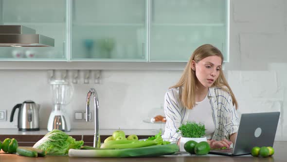 Vegetarianism Female Prepares a Salad in the Kitchen Cuts Herbs and Green Vegetables to Make a