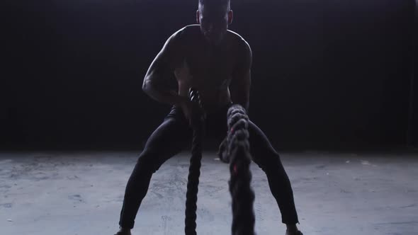 Shirtless african american man exercising battling ropes in an empty building