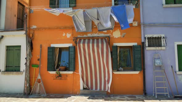 Shabby Facade of Old Orange House With Drying Laundry and Fishing Equipment