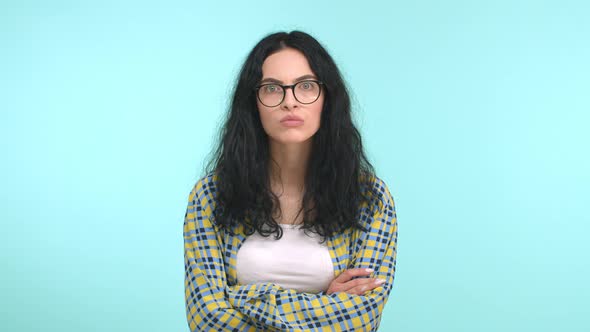 Young Attractive Woman with Long Dark Hair and Glasses Staring Serious and Pensive at Camera