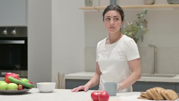 Indian Woman Feeling Worried While Standing in Kitchen