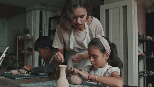 Woman Helping Girl on Pottery Lesson