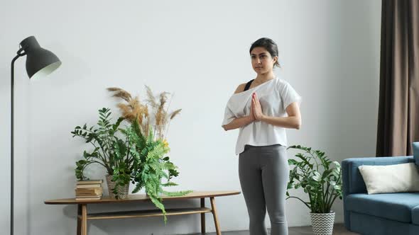 Young Indian Woman Meditating Standing on Carpet and hand Namaste, Doing balance