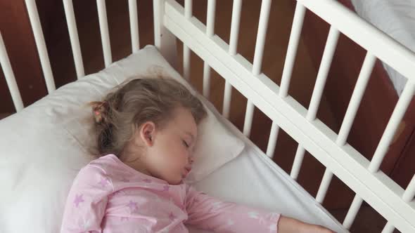 Close Up Authentic Cute Caucasian Little Preschool Child Girl Sleep Sweetly in White Crib on Pajama