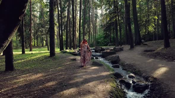 Smiling Young Woman Walking Though Forest near the river