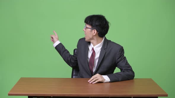 Young Asian Businessman As Newscaster Talking and Presenting Something at the Back