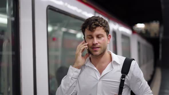 Businessman Talking on Cellphone Near Train