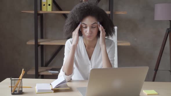 Tired Stressed Mixed Race Woman Sitting at Table Near Laptop Touch Massaging Temples Suffers 