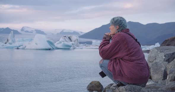 Cool Girl Crouching To Watch Icebergs In Sea