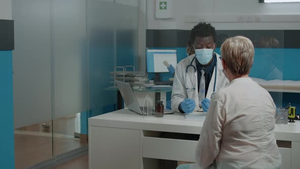 Young Medic Wearing Face Mask While Consulting Elder Patient