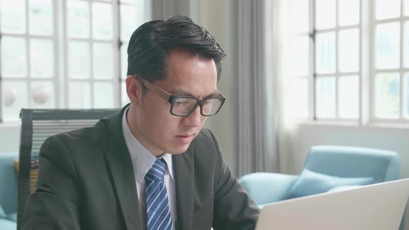 Asian Businessman Typing On Computer While Working At Home