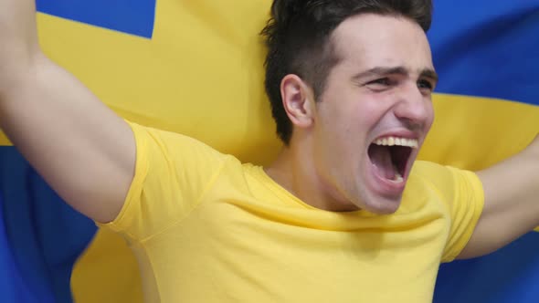 Swedish Young Man Celebrating while Holding the Flag of Sweden