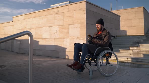 Handicapped Man in Wheelchair with Phone on City Stairway