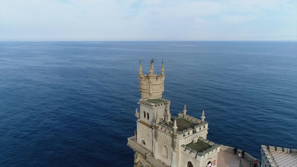 Ancient Beautiful Castle and People Inside on Background of Blue Sea and Sky.