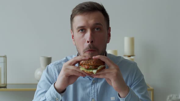 Young Man Holding a Piece of Hamburger