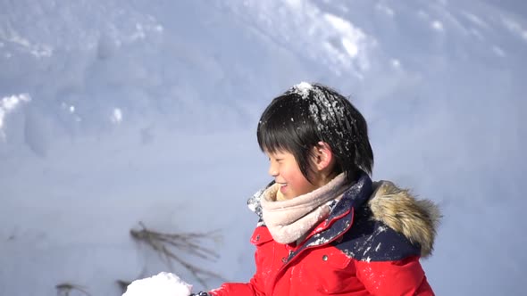 Cute Asian Child Wearing Winter Clothes Playing On Snow In The Park