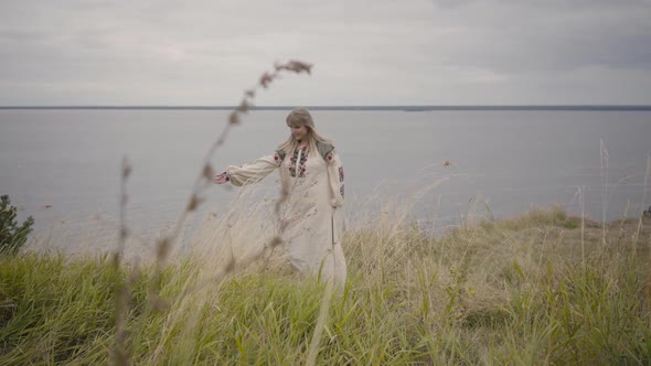 Attractive Blond Girl in Beautiful Long White Summer Dress with Embroidery Dancing and Spinning