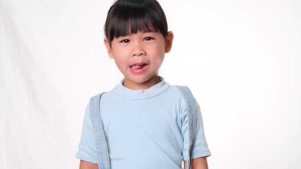 Happy little girl smiling showing her thumb on white background in studio. Healthcare concept