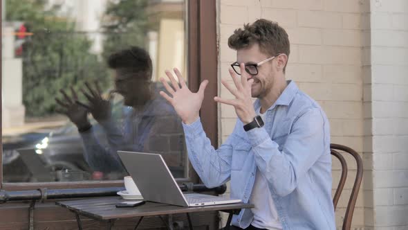 Young Man Celebrating Success on Laptop, Sitting Outdoor