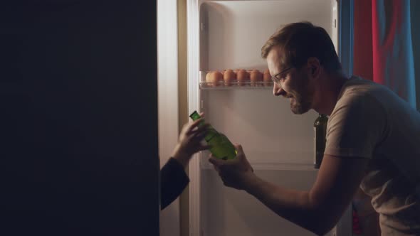 a Man Opens the Refrigerator at Night to Get a Bottle of Beer