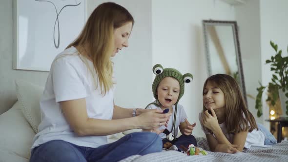 adorable mother and her children, daughter and little son play toys on fingers