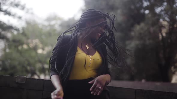 Cheerful black woman moving head with flying hair on street