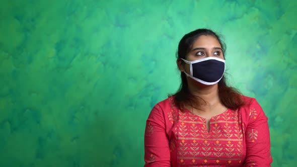 Bored Indian girl wearing protective mask for prevention of Covid-19 coronavirus at home due to Lock