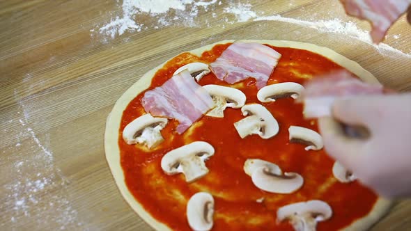 Putting mushrooms and bakon on pizza dough 