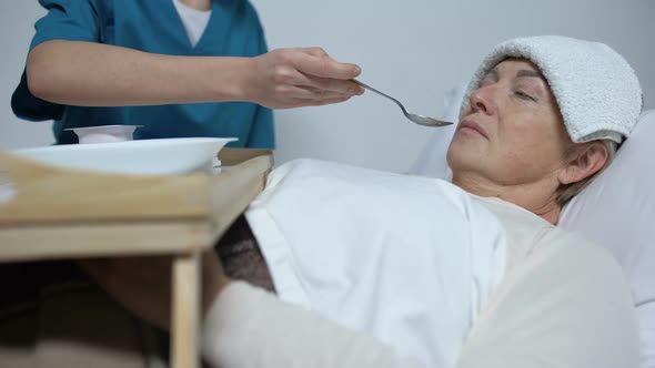 Terminally Ill Woman With Compress on Forehead Refusing From Hospice Porridge