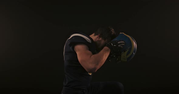 Portrait of American Football Sportsman Player Putting on and Tightening His Football Helmet on