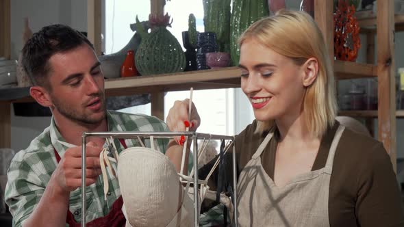 Professional Potter Helping His Female Student at the Workshop