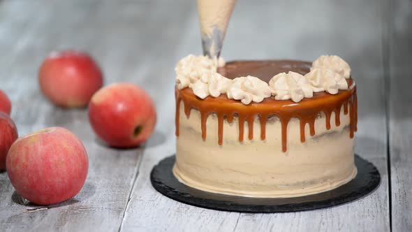 Hands squeezing whipped cream pastry bag to decorate the cake topping