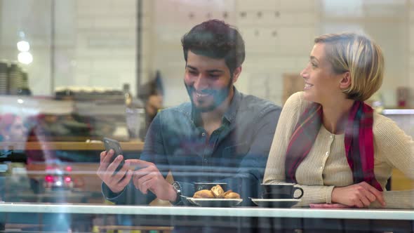 Technology. Happy people with mobile phone having fun in cafe