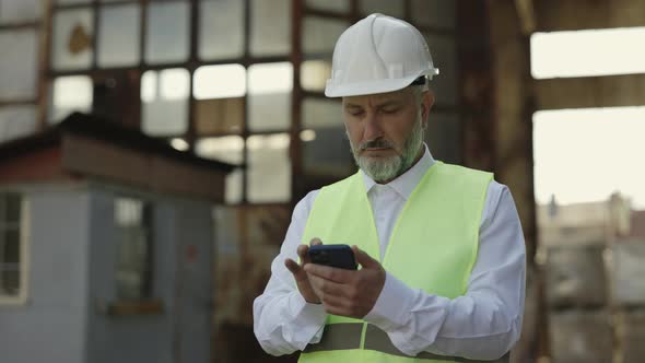 Foreman Using Mobile While Standing at Construction Site